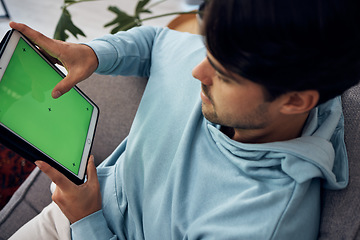 Image showing Tablet, green screen and a man playing games on a sofa in the living room of his home from above. Technology, gaming and young gamer using a display or screen with tracking markers for entertainment