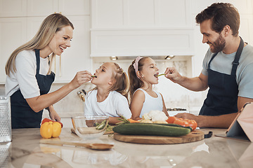 Image showing Family, kitchen and vegetables or children feed health food, nutrition, cooking or together. Parents, daughter or smile for dinner or happy eating, salad or vegan recipe or natural diet, meal in home