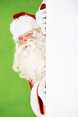 Image showing Santa claus, hiding and wall portrait for Christmas celebration, mockup space or wink. Male person, secret peek and emoji face for festive seasons or holiday, green studio background or signboard