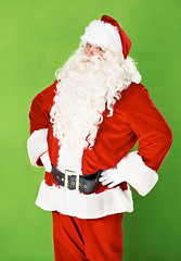 Image showing Santa claus, hands and hips in studio portrait for holiday celebration, festive season or gift giving. Father Christmas, face and costume suit for winter vacation fun, on green background for joy