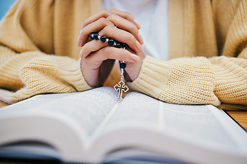 Image showing Bible, rosary and hands of woman in prayer, studying religion at desk in home with Christian faith and knowledge of God. Reading, hope and girl at table with holy book for praise, gospel and beads.