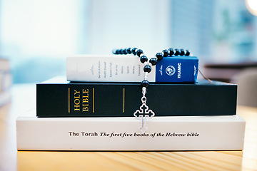 Image showing Books, stack and closeup on table for faith, Abrahamic religion or rosary with crucifix for study in home. Knowledge, holy spirit and education with cross for Jesus, Muhammad or Moses with solidarity