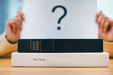 Image showing Books, stack and closeup on desk for faith, Abrahamic religion and question mark on poster for study in home. Person, holy spirit and education for choice with Jesus, Moses and worship God with sign