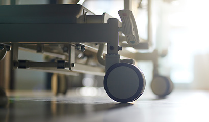 Image showing Hospital, bed and wheels of stretcher on floor, ground or interior of empty clinic with equipment. Healthcare, transport and closeup of medical wheeling chair or gurney in medical furniture and room