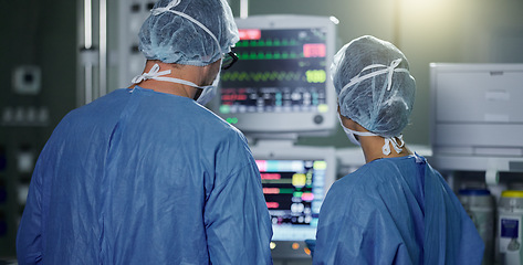 Image showing Teamwork, screen monitor or surgeon in surgery procedure or healthcare operation in hospital. Night, back view or doctors in face mask working or helping in dark operating room in medical clinic