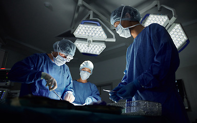 Image showing Teamwork, emergency and doctors or people in surgery procedure or healthcare operation in hospital. Night, low angle or surgeon in face mask or gloves help in dark operating room in medical clinic