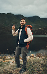 Image showing Happy man, portrait and peace sign on mountain for hiking, travel or outdoor backpacking in nature Male person or hiker smile with backpack for trekking, journey or adventure in happiness by the lake