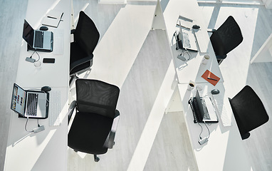 Image showing Top view, empty office interior and table with laptops in coworking space in creative startup company. Above, desk and computer in room with furniture, chairs or modern design for business technology