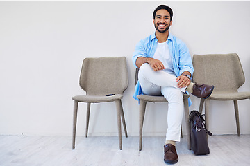 Image showing Smile, waiting and man in the office for recruitment meeting with human resources for hiring. Confidence, professional and person sitting on a chair for job interview in hallway in modern workplace.