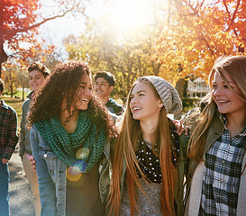 Image showing Teenager, walking and talking with friends in park, nature or social group outdoor in autumn with diversity. Happy, youth or kids relax in fall with a joke, best friend or conversation in community