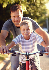 Image showing Bicycle, ride and father help child with bike and learning on the road and parent support kid in vacation or holiday. Smile, development and dad together with son and teaching outdoor skills