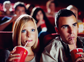 Image showing Cinema, movie and couple with drink, watching film and concentration on romantic evening together. Date night, man and woman in theater with soda, attention and sitting in auditorium to relax at show
