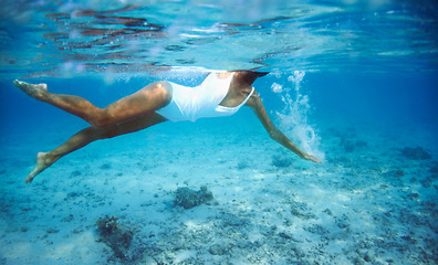 Image showing Underwater, summer and a woman swimming in the ocean for travel, freedom or adventure in tropical nature. Sea, swimwear and a person diving to explore or discover a deep blue wilderness environment