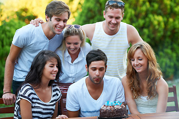 Image showing Birthday, friends and blow candles outdoor for celebration, surprise or party with milestone or happiness. Cake, men and women in backyard of home or nature with gathering or social event with smile