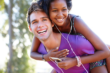 Image showing Fitness, smile and happy couple with piggyback hug in a park for training, bond or fun. Interracial, love and face of active man with back ride for woman with music, earphones or audio mp3 player