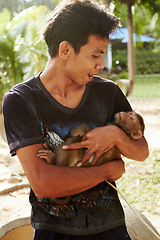 Image showing Zoo, animal and man with monkey in nature for care, conservation and wildlife rescue. Sanctuary, travel and happy person with macaque in environment, ecosystem and outdoors in Thailand for tourism