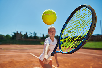 Image showing Close up photo of a young girl showing professional tennis skills in a competitive match on a sunny day, surrounded by the modern aesthetics of a tennis court.