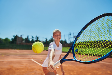 Image showing Close up photo of a young girl showing professional tennis skills in a competitive match on a sunny day, surrounded by the modern aesthetics of a tennis court.