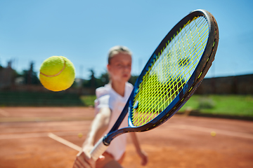 Image showing Close up photo of a young girl showing professional tennis skills in a competitive match on a sunny day, surrounded by the modern aesthetics of a tennis court.