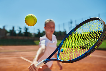 Image showing Close up photo of a young girl showing professional tennis skills in a competitive match on a sunny day, surrounded by the modern aesthetics of a tennis court.