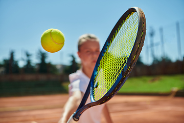 Image showing Close up photo of a young girl showing professional tennis skills in a competitive match on a sunny day, surrounded by the modern aesthetics of a tennis court.