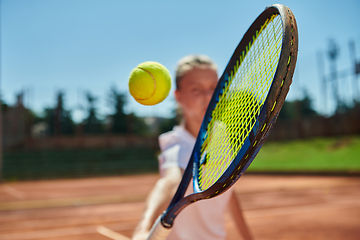 Image showing Close up photo of a young girl showing professional tennis skills in a competitive match on a sunny day, surrounded by the modern aesthetics of a tennis court.