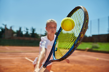 Image showing Close up photo of a young girl showing professional tennis skills in a competitive match on a sunny day, surrounded by the modern aesthetics of a tennis court.