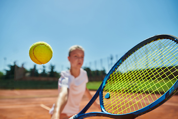 Image showing Close up photo of a young girl showing professional tennis skills in a competitive match on a sunny day, surrounded by the modern aesthetics of a tennis court.