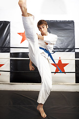 Image showing Man, karate and high kick for martial arts in ring, self defense or jiujitsu training for fighting match. Male person, athlete or fighter in MMA boxing, muay thai or fitness practice at dojo or gym