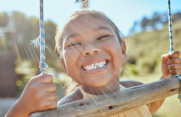 Image showing Smile, teeth and small girl on swing in outdoor park, happiness fun and playing outside in Indonesia. Health, happy face and a portrait of a young child swinging in garden at home in summer holiday.