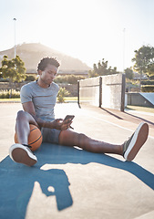 Image showing Basketball, phone and man relax on social media, internet and reading news on app outdoor on a court. Black man with 5g smartphone after sport training, exercise and game at sports club in summer