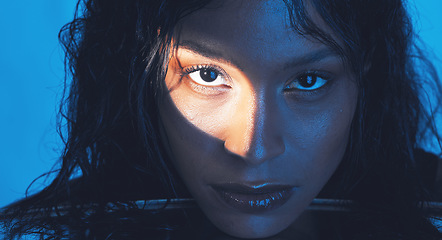 Image showing Beauty, cosmetics and portrait of a model with a light reflection on her face in the studio. Spotlight, skincare and young woman from Puerto Rico with natural skin isolated by a blue background.