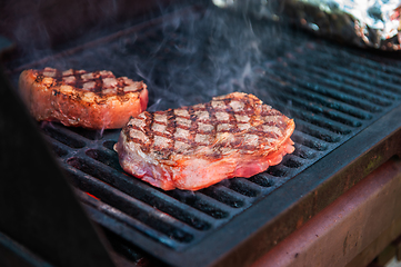 Image showing Beef steaks on the grill with flames