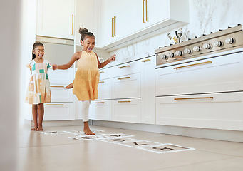 Image showing Hopscotch, fun and children playing a game together in the kitchen of their modern family home. Happy, smile and girl kids or sisters jumping on numbers to play, bond and for entertainment at a house