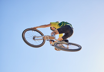 Image showing Bicycle, cyclist man and jump of adrenaline junkie from below riding in a competition with copyspace. Extreme sport, bicycle and cycling man stunt while on bike against a blue sky background