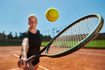 Image showing Close up photo of a young girl showing professional tennis skills in a competitive match on a sunny day, surrounded by the modern aesthetics of a tennis court.