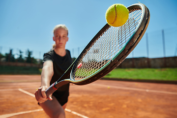 Image showing Close up photo of a young girl showing professional tennis skills in a competitive match on a sunny day, surrounded by the modern aesthetics of a tennis court.