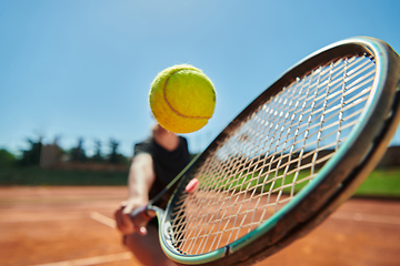 Image showing Close up photo of a young girl showing professional tennis skills in a competitive match on a sunny day, surrounded by the modern aesthetics of a tennis court.