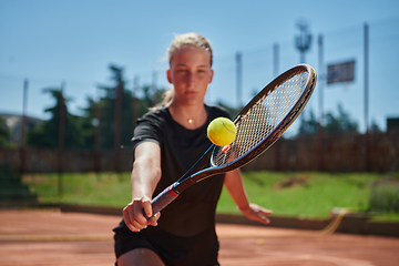 Image showing Close up photo of a young girl showing professional tennis skills in a competitive match on a sunny day, surrounded by the modern aesthetics of a tennis court.