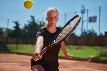 Image showing A young girl showing professional tennis skills in a competitive match on a sunny day, surrounded by the modern aesthetics of a tennis court.