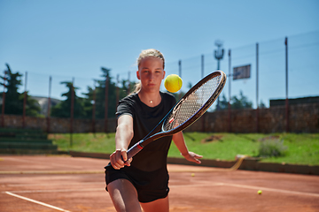 Image showing A young girl showing professional tennis skills in a competitive match on a sunny day, surrounded by the modern aesthetics of a tennis court.