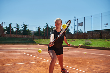 Image showing A young girl showing professional tennis skills in a competitive match on a sunny day, surrounded by the modern aesthetics of a tennis court.