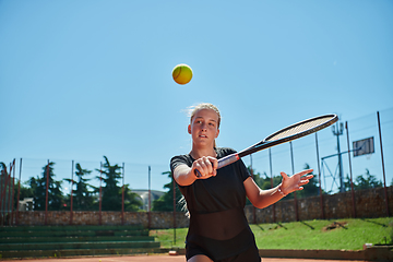 Image showing A young girl showing professional tennis skills in a competitive match on a sunny day, surrounded by the modern aesthetics of a tennis court.