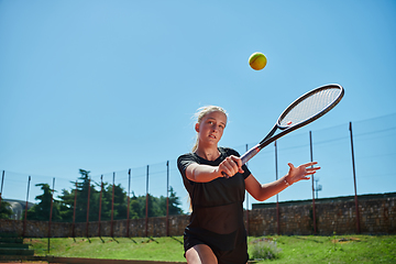 Image showing A young girl showing professional tennis skills in a competitive match on a sunny day, surrounded by the modern aesthetics of a tennis court.