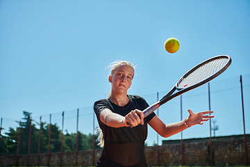 Image showing A young girl showing professional tennis skills in a competitive match on a sunny day, surrounded by the modern aesthetics of a tennis court.