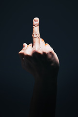 Image showing Middle finger, rude and disrespect with the hand of a man in studio on a dark background with light highlight. Angry, sign and gesture with a male showing hatred with an obscene or aggressive symbol