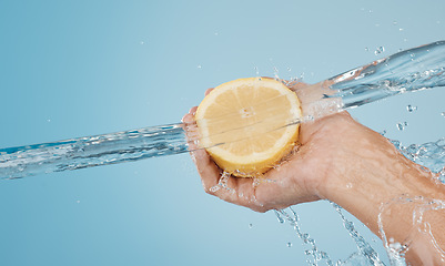 Image showing Water, splash and beauty with hands and lemon for health, wellness and hydration. Vitamin c, refreshing or nutrition with citrus fruits and model against blue background for natural, vitality or diet