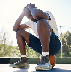 Image showing Depression, sport and man on basketball court for fitness outdoors. Stressed black athlete, mental health and tired after wellness workout or exercise training burnout in sports park with ball