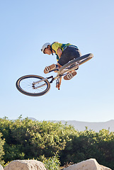 Image showing Bike, extreme sport and outdoor fitness, man does dangerous stunt, sports motivation and training in nature. Exercise, athlete with mountain bike, risk and active with energy and jump over rocks.
