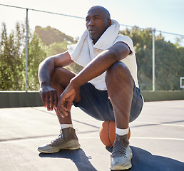 Image showing Relax, fitness and man on a basketball after workout, sitting and stop for a break at basketball court, towel and sweat. Basketball player, rest and tired after training, exercise and sports practice